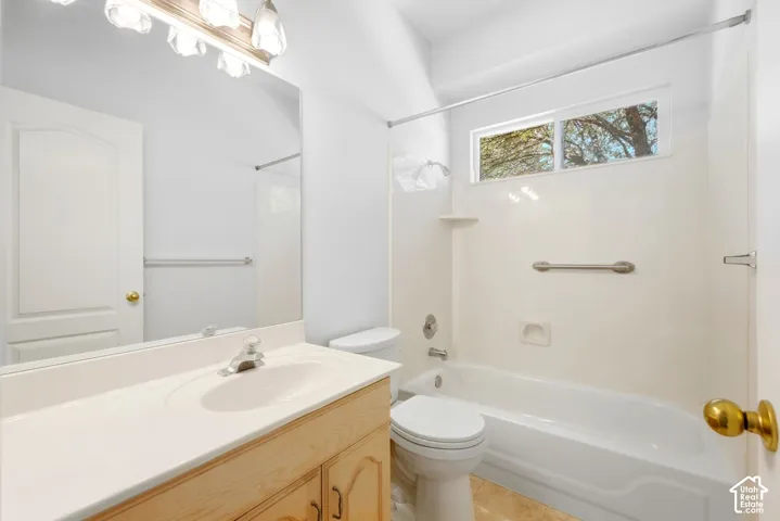Bathroom featuring a single vanity, integrated sink, light wood-finish cabinetry, and a full bathtub with shower