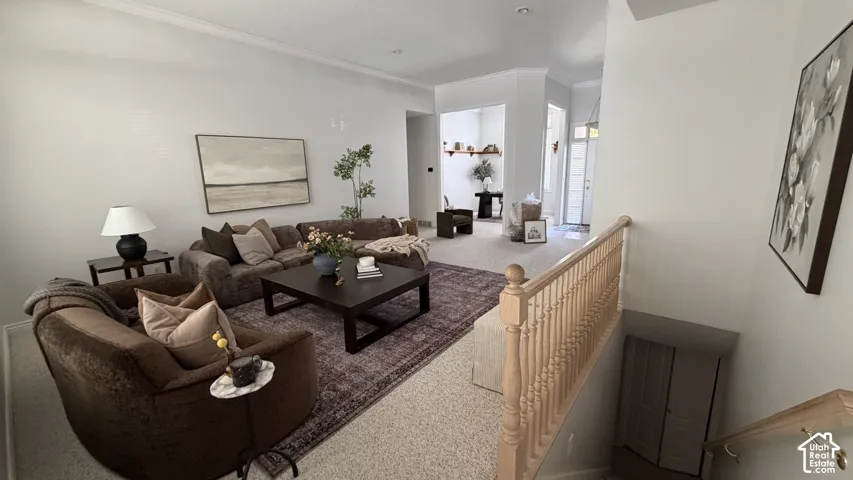 Spacious living area with crown molding, light-toned walls, and wood-finish accent tables