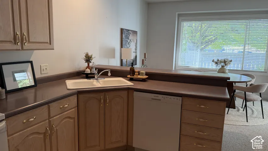 Kitchen featuring wood cabinetry with brass hardware, a corner sink, and a built-in dishwasher