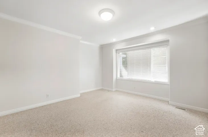 Recessed lighting, crown molding, a large window with blinds, and light-toned carpeting