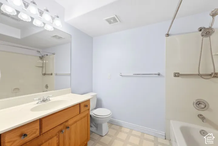 Bathroom featuring a light wood-finish vanity, a white countertop with an integrated sink, a large wall-mounted mirror, and a shower/tub combination with a handheld showerhead