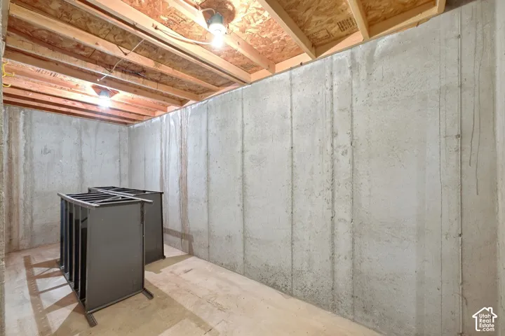 Unfinished basement featuring concrete foundation walls and exposed wood ceiling joists