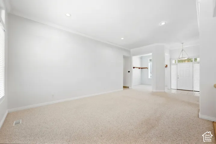 Recessed lighting, crown molding, and neutral carpeting