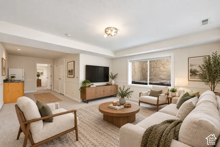 Recessed lighting, neutral-toned carpeting, built-in wet bar, wood-finish cabinetry, and a large window