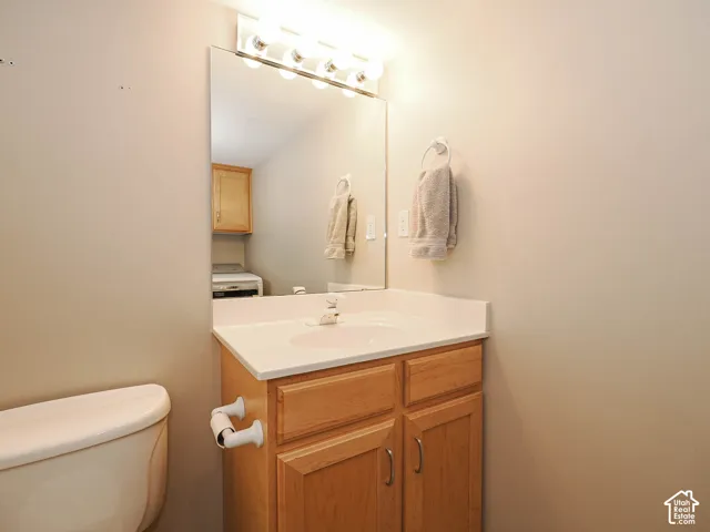Bathroom vanity with a white countertop and integrated sink, complemented by natural wood-finish cabinetry