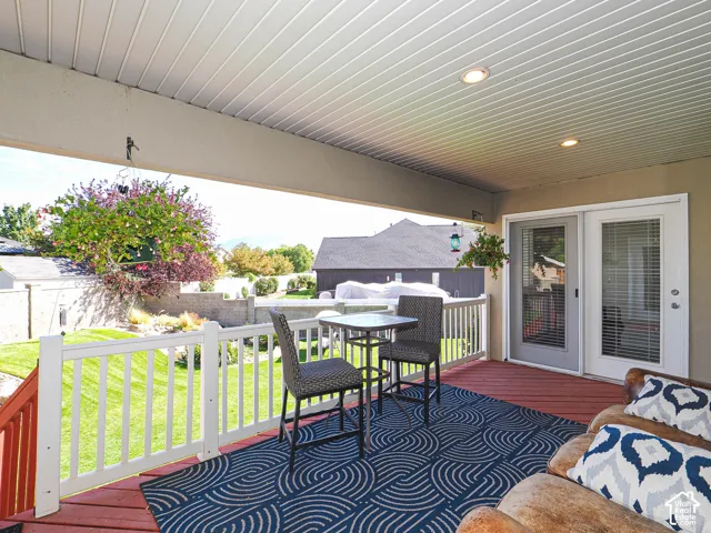 Covered outdoor deck with a red-stained surface, white railing, and recessed ceiling lighting