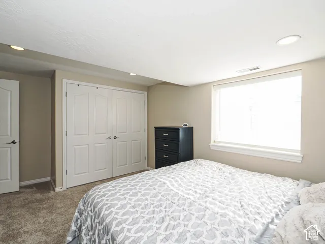 Recessed lighting, window with blinds, bi-fold closet doors, wall-to-wall carpeting, and a white interior door