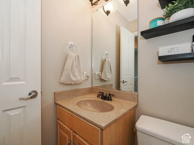 Vanity with a neutral-toned countertop and integrated sink, bronze-finish faucet, and coordinating wall-mounted light fixture