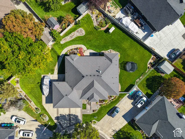 Property featuring a multi-gabled roof, expansive green lawn, mature trees, paved driveways, and a substantial storage shed