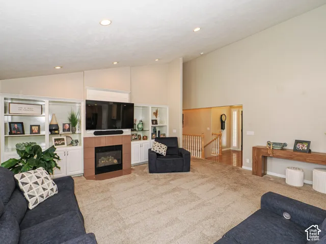 Vaulted ceiling, recessed lighting, built-in shelving, gas fireplace, and wood-finish handrailing