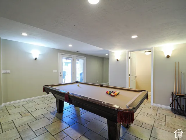 Recessed ceiling lighting, wall sconces, French doors with blinds, and tile flooring
