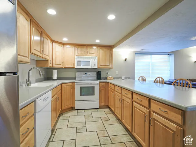 U-shaped kitchen with wood cabinetry, light-toned countertops, and recessed lighting
