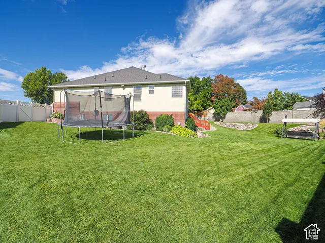 Expansive backyard featuring a manicured lawn, established landscaping, and a tiered design with retaining walls