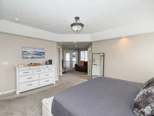 Plush carpet flooring, tray ceiling, recessed lighting, and a drum pendant light fixture