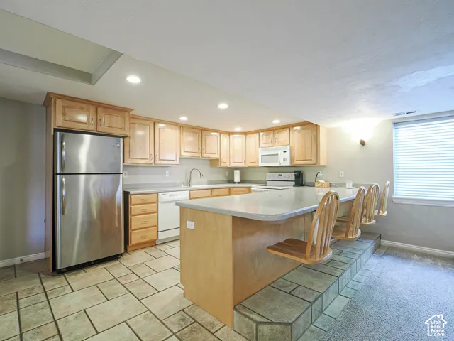 Kitchen featuring stainless steel appliances, light wood-finish cabinetry, a large island with countertop seating, and recessed lighting