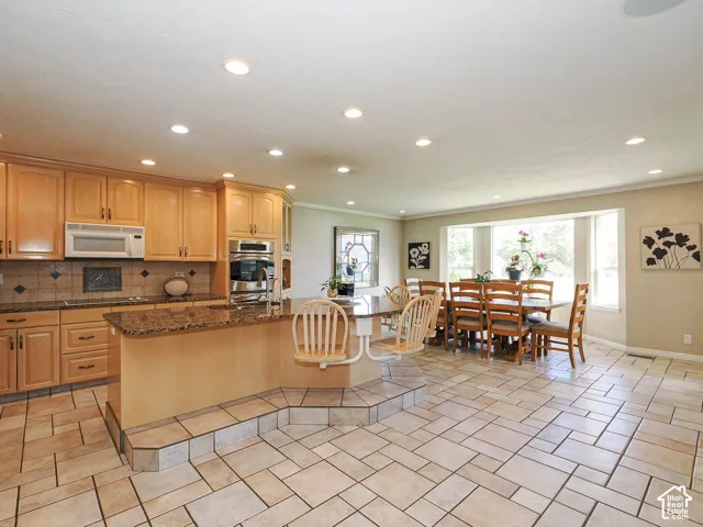 Recessed lighting, wood cabinetry, built-in stainless steel appliances, granite countertops, and a bay window