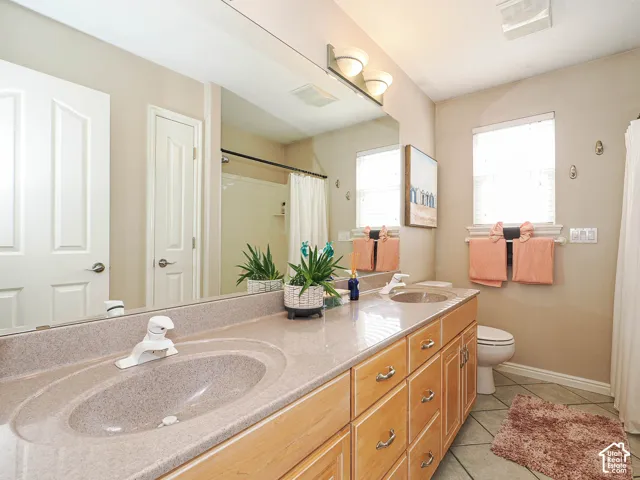 Bathroom featuring a double vanity with integrated sinks, wood-finish cabinetry, and a large mirror