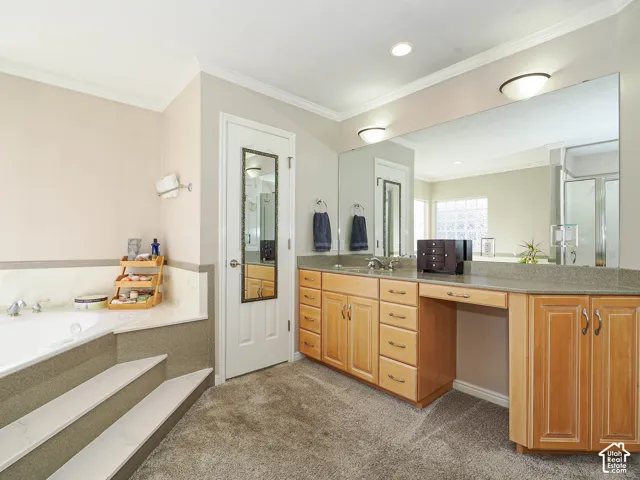 Built-in vanity with light wood cabinetry, dual sinks, and an integrated seating area
