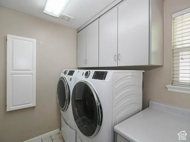 Built-in white cabinetry, textured ceiling, fluorescent overhead lighting, window with blinds, and white countertop space