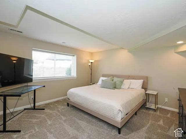 Recessed lighting, window with blinds, tray ceiling, and neutral-toned wall paint