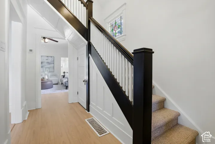 Hardwood-style flooring, paneled walls, and a staircase featuring a dark newel post and balustrade with white spindles