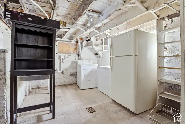 Exposed ceiling joists with white-painted finish, concrete flooring, built-in shelving, and a visible utility area