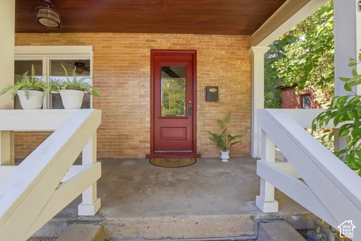 Brick exterior with a prominent red entry door, white railings, a mounted mailbox, and a finished wood porch ceiling