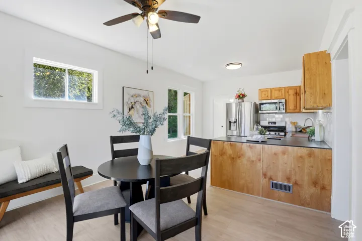 Open-concept living space featuring wood-finish flooring, white walls, and a ceiling fan
