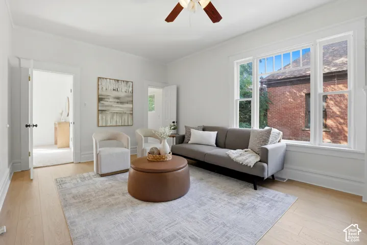 Bright living space featuring wood-finish flooring, white trim, and a ceiling fan