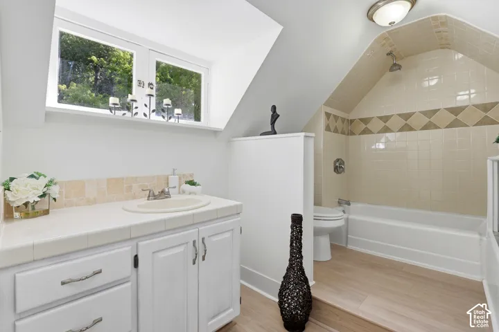 White vanity with integrated sink, tile countertop, and a tiled backsplash