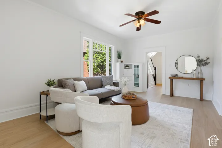 Bright living area featuring wood-finish flooring, a ceiling fan with integrated lighting, and multiple windows