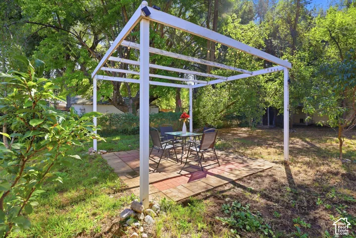 White pergola structure with string lighting over a paver patio