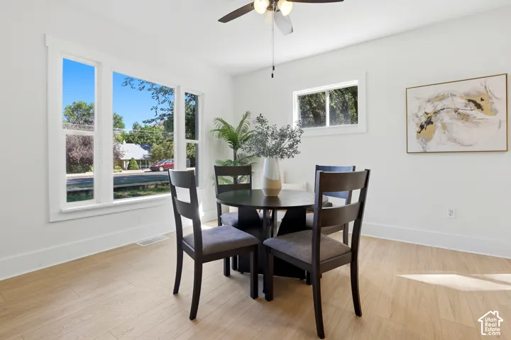 Light wood-finish flooring, white walls, and a ceiling fan with integrated lighting