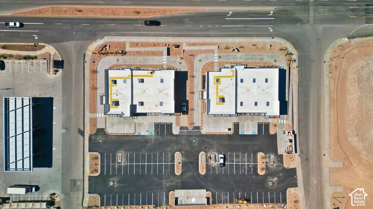 Two commercial buildings with flat roofs, expansive paved parking areas, and adjacent roadways