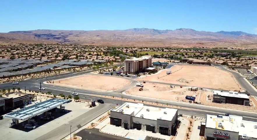 Expansive undeveloped lot with surrounding commercial and residential properties, featuring mountain scenery in the distance