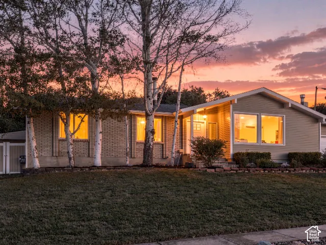 Mid-century modern residence featuring a brick facade, large picture windows, a covered entry, and mature landscaping
