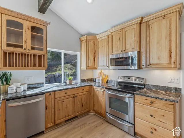 Kitchen featuring natural wood cabinetry, stainless steel appliances, granite countertops, a stainless steel sink with a black gooseneck faucet, and wood-finish flooring