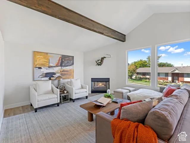 Vaulted ceilings featuring a wood beam, wood-finish flooring, and a built-in fireplace