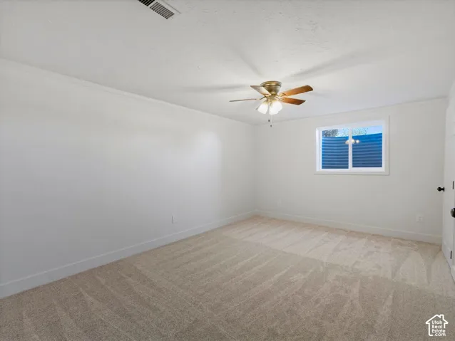 Neutral-toned carpeting, white painted walls, and a ceiling fan with integrated lighting