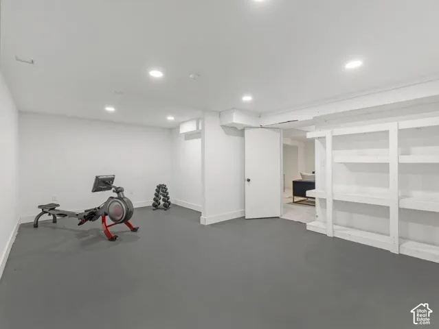 Recessed lighting illuminates the expansive room featuring built-in shelving, durable flooring, and a solid-core door