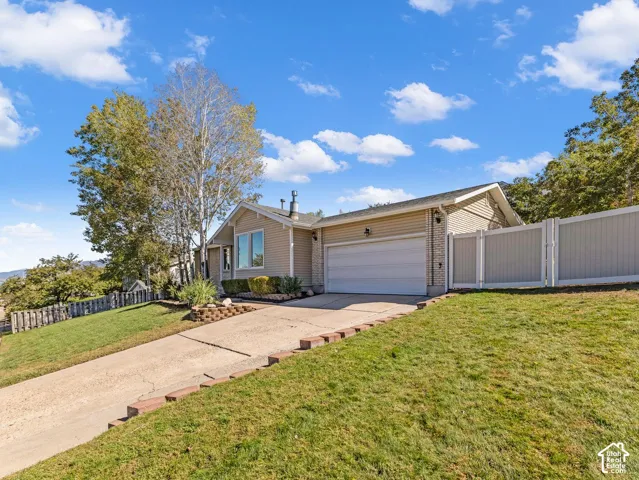 Siding exterior with a visible garage, concrete driveway, and established landscaping