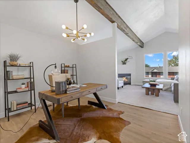 Vaulted ceiling with exposed wood beam, modern sputnik chandelier, wood-finish flooring, built-in fireplace, and expansive windows