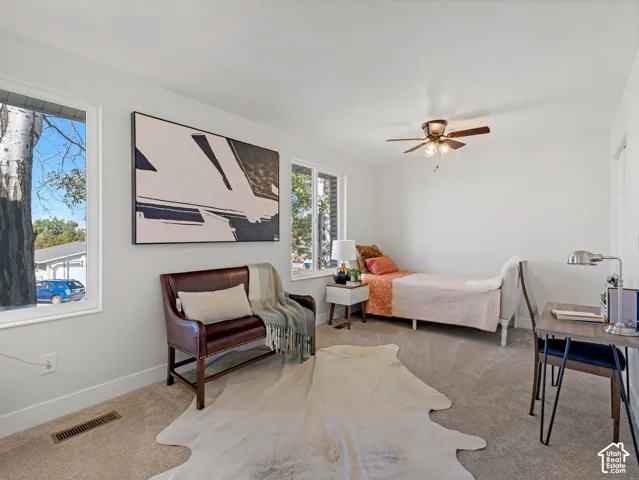 White walls, light-colored carpeting, multiple windows, and a ceiling fan