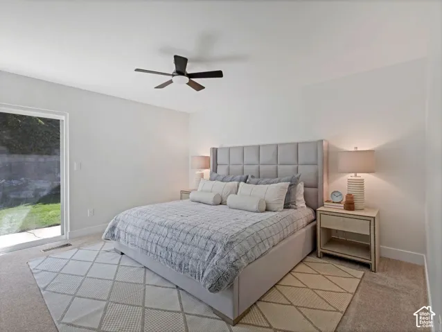 Bright sleeping area with a ceiling fan, light-toned carpeting, and a sliding glass door leading to the exterior
