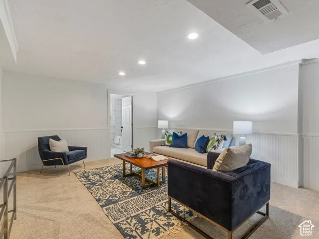 Recessed lighting illuminates a spacious room featuring white beadboard paneling and light-toned carpeting
