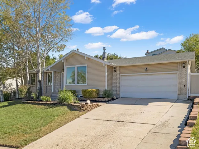 Beige siding exterior with white trim, a two-car garage, and a concrete driveway
