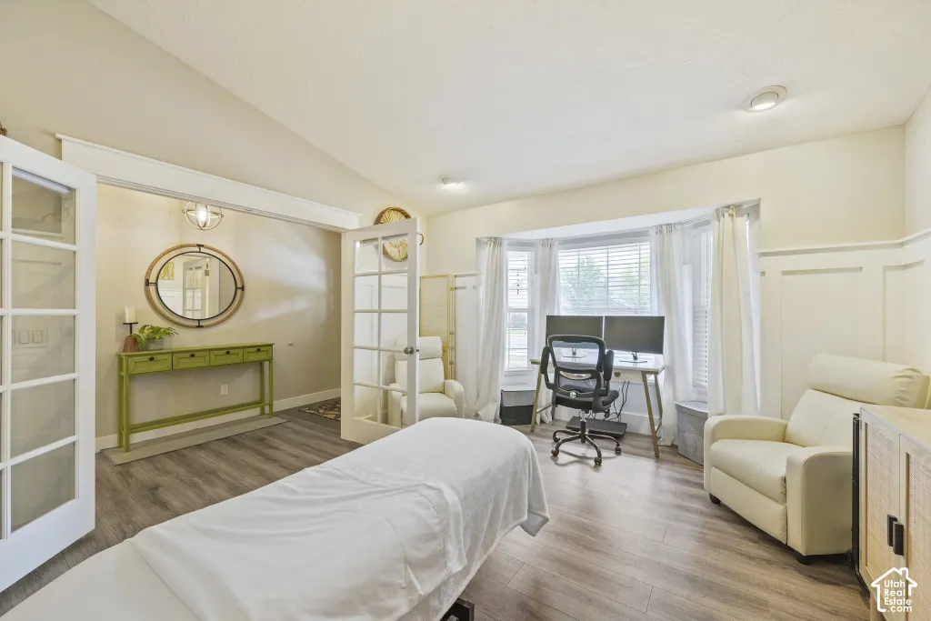 Wood-finish flooring, bay window, recessed lighting, and white French doors