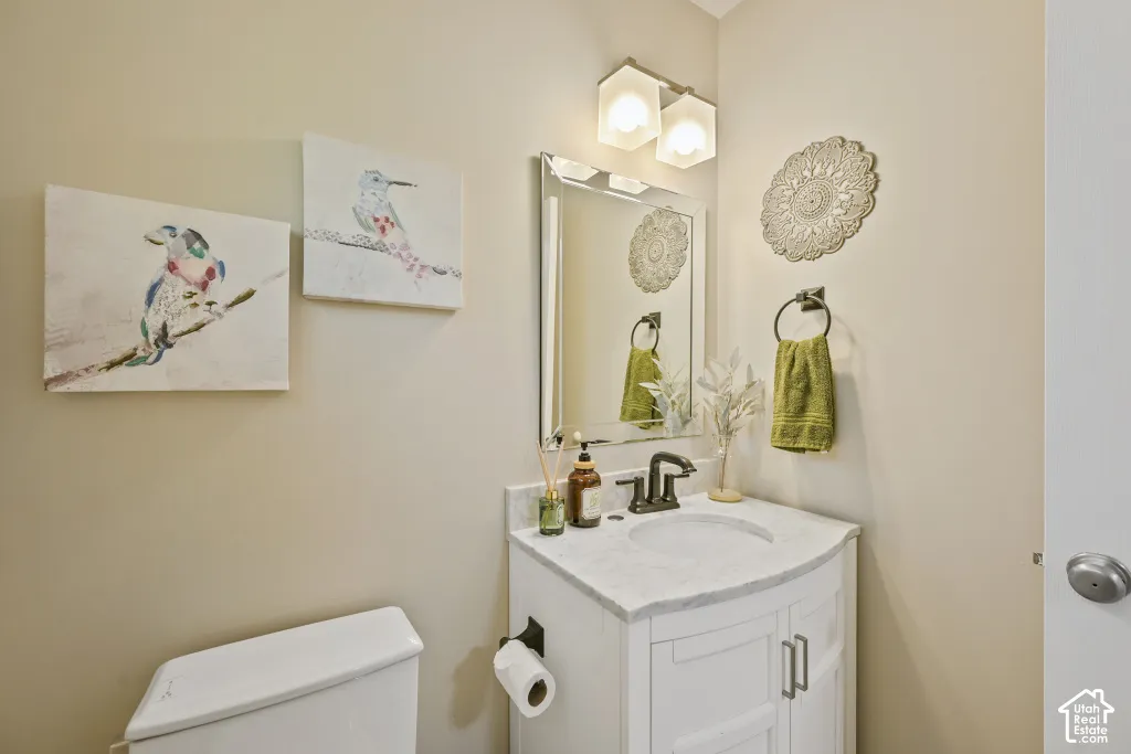 White vanity with a curved marble-patterned countertop, integrated sink, and bronze-finish faucet