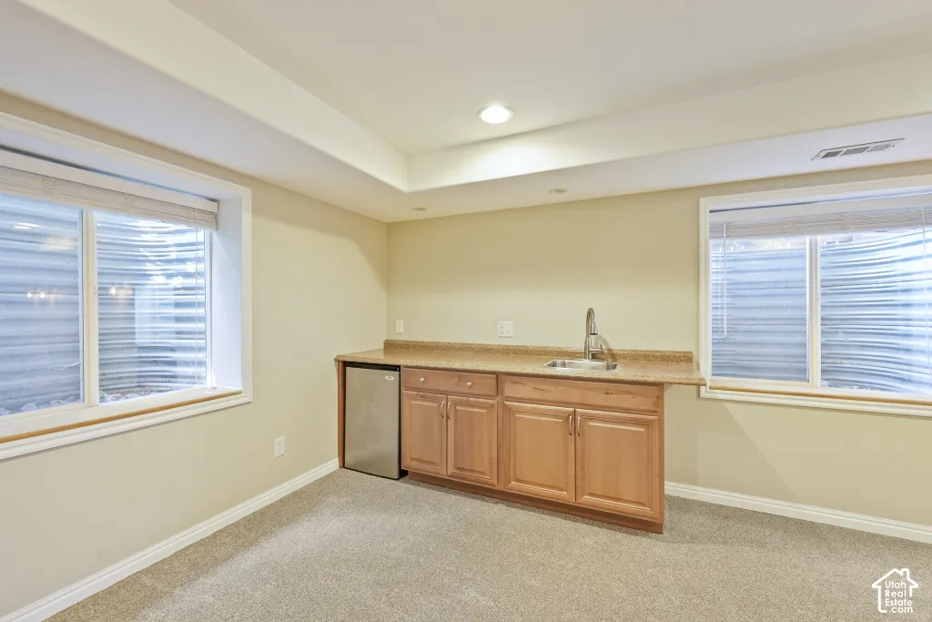 Built-in cabinetry with a sink and countertop, integrated mini-refrigerator, recessed lighting, and two windows