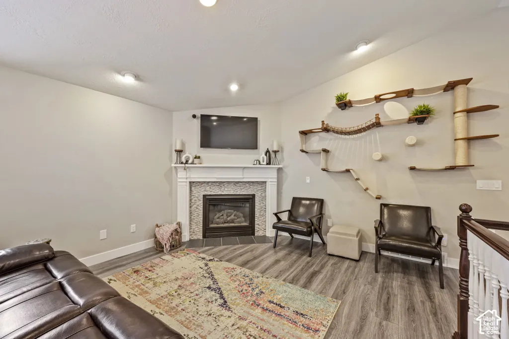 Fireplace with a tile surround and white mantel, wood-finish flooring, recessed lighting, and a white balustrade